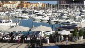 A marina with numerous boats docked, outdoor seating areas, and a few people walking around. - HEC Beach Apartment Marina Vilamoura, sea side, pool, golf, beach, boat trips,  (Quarteira)