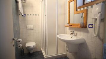 A bathroom with a toilet, a shower enclosure, a sink, and a mirror.