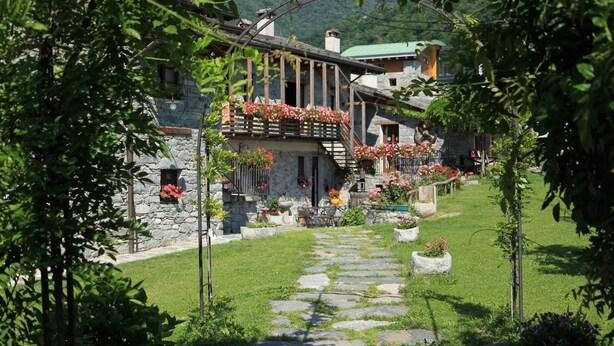 A stone building with a stone pathway leading to a wooden door. - Le Case dei Baff (Ardenno)