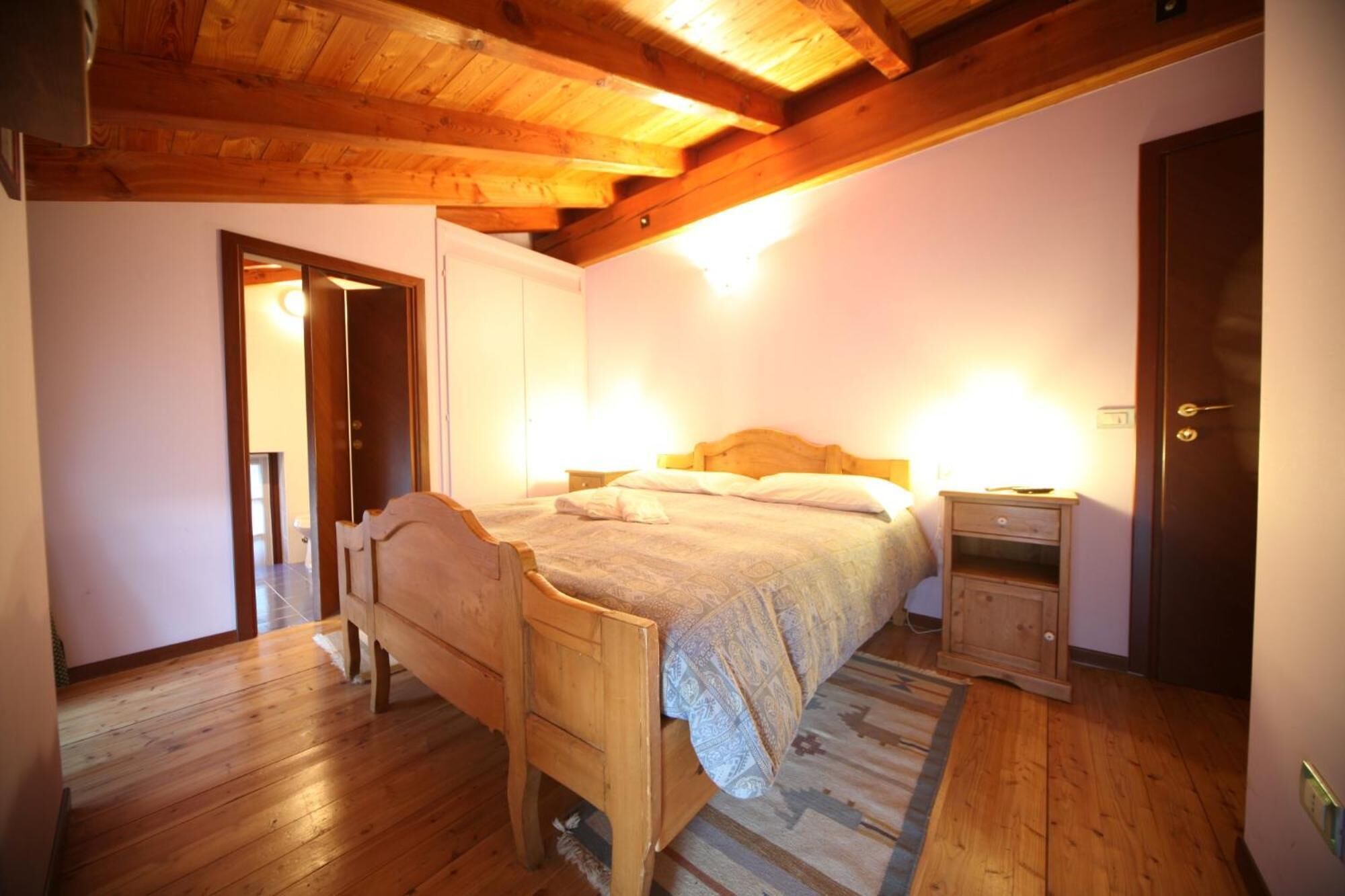 Un dormitorio con una cama de madera, una mesita de noche, un aparador y una puerta.