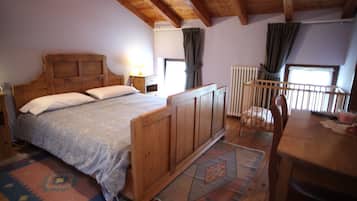 Una cama de madera con cabecera, una mesita de noche, una mesa de madera y una cuna.