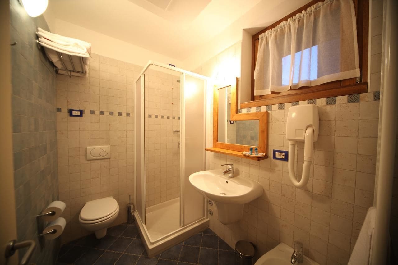 A bathroom with a toilet, sink, shower, and a towel rack.