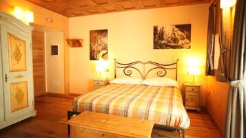 Un dormitorio con cama, mesitas de noche, armario y dos lámparas de pared.