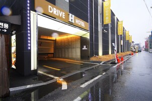 A hotel entrance with a sign reading "Drive H Hotel" and multiple yellow banners.