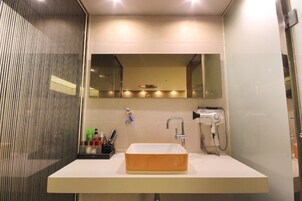 A modern bathroom with a rectangular sink, a handheld showerhead, and a mirror above the sink.