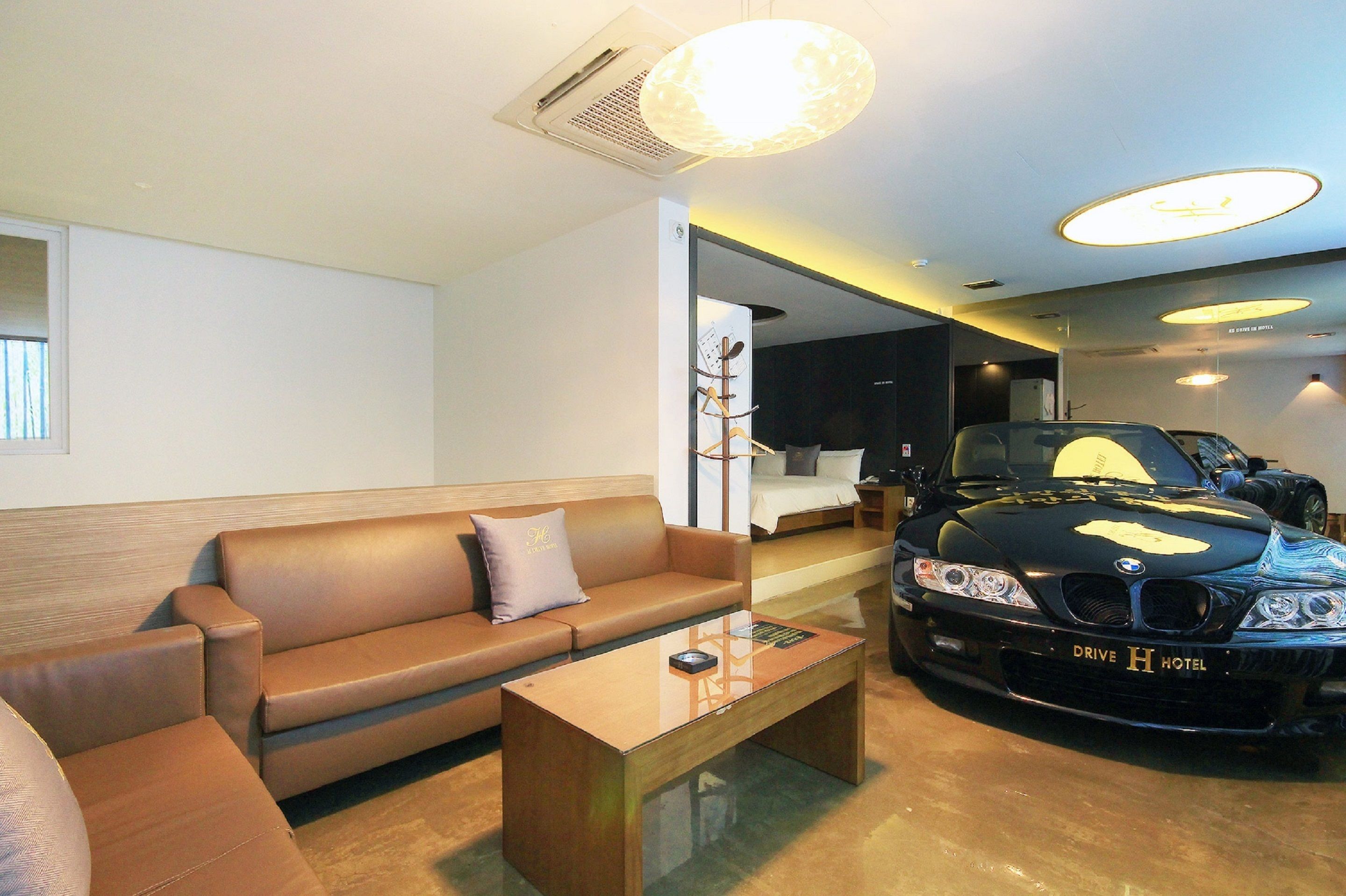 Et moderne hotelværelse med en lædersofa, et glastæppe og en sort BMW i baggrunden.