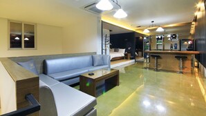 Un espacio de sala moderno con sofá, una mesa de centro y una zona de bar con taburetes.