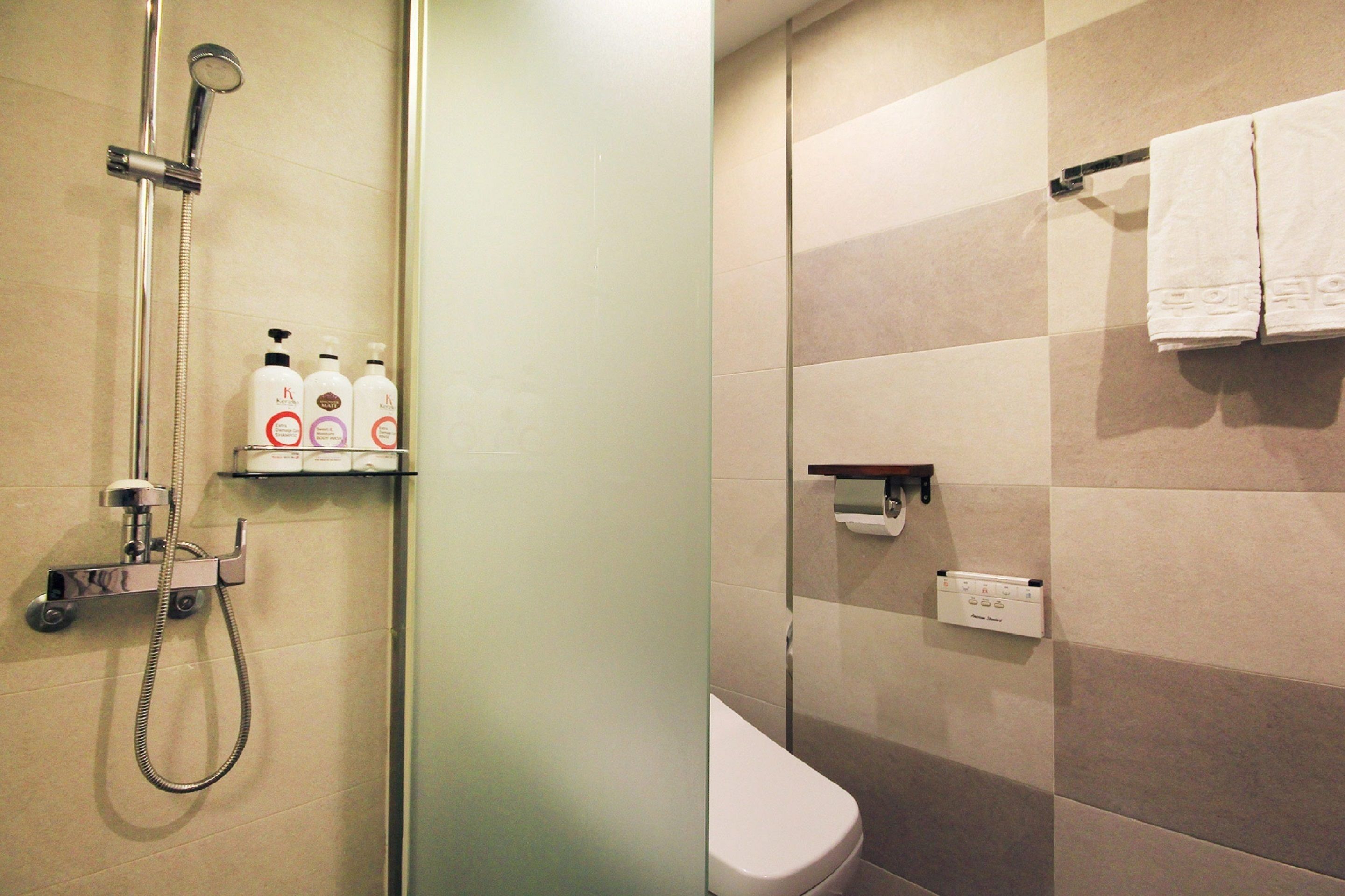 Une salle de bain avec douche, toilettes et une étagère contenant des articles de toilette.