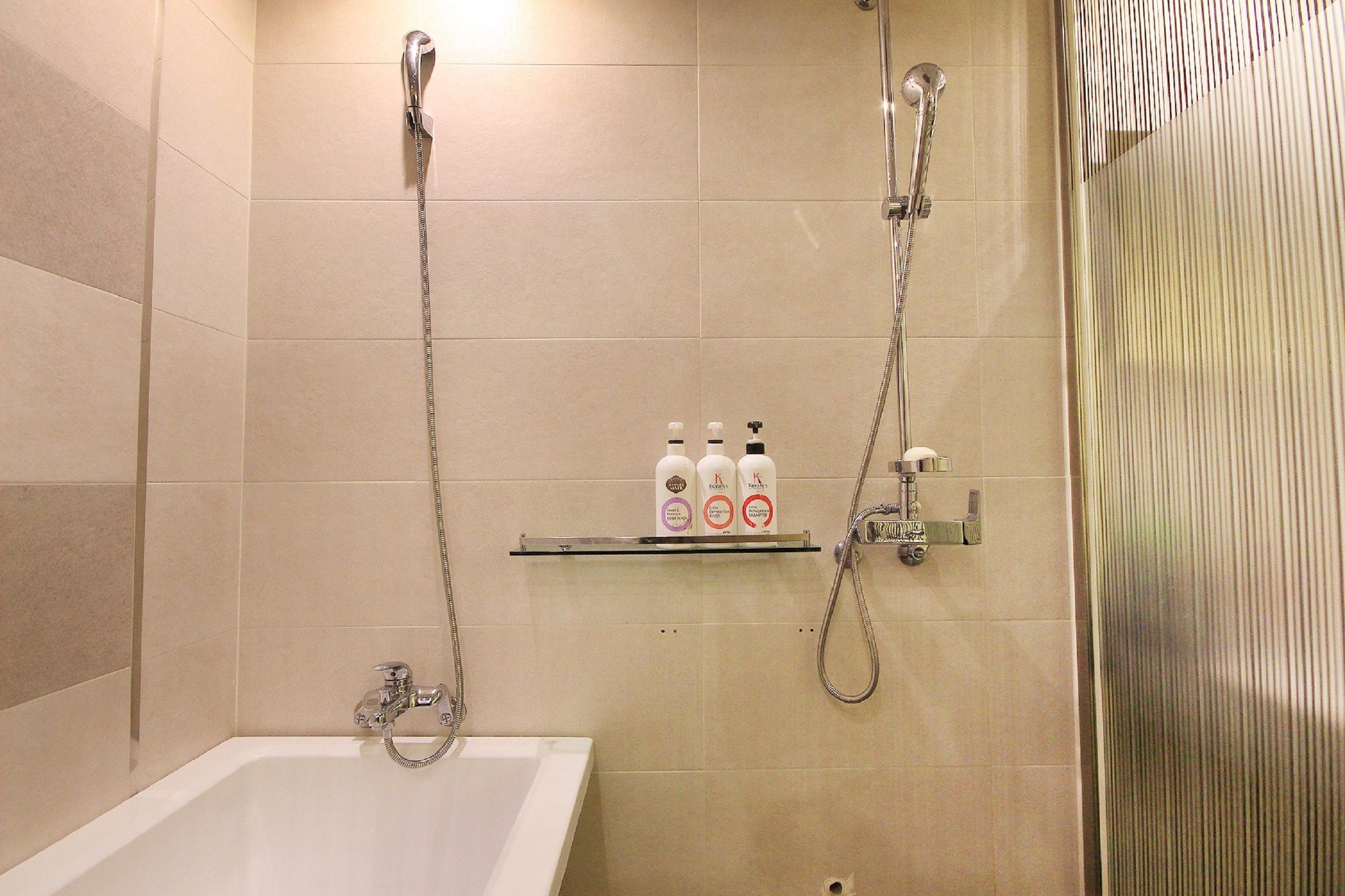 A bathroom with a bathtub, a shower, and a shelf with toiletries.