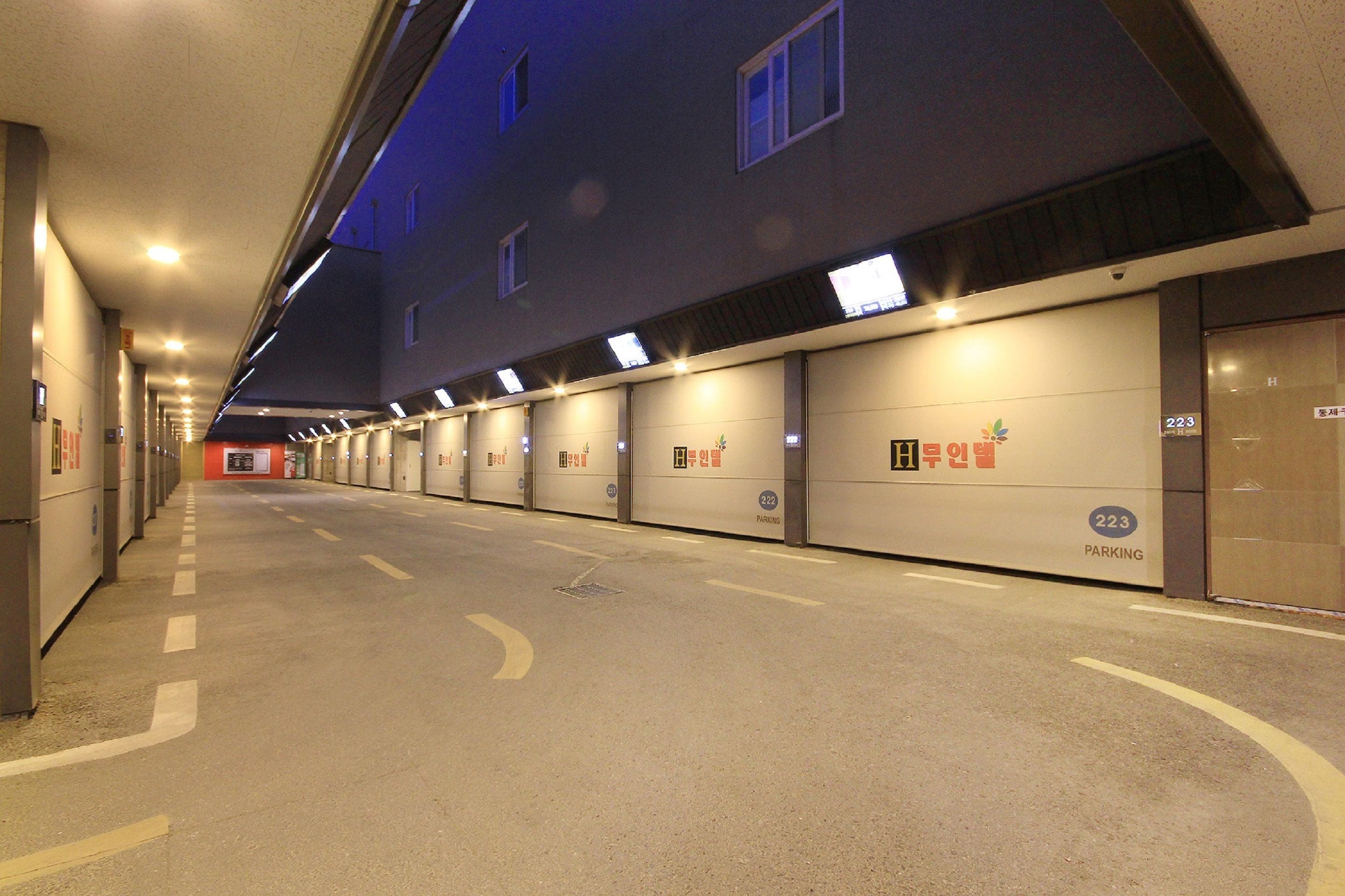 Una larga hilera de puertas de garaje con números iluminados, que señalan los espacios de estacionamiento.