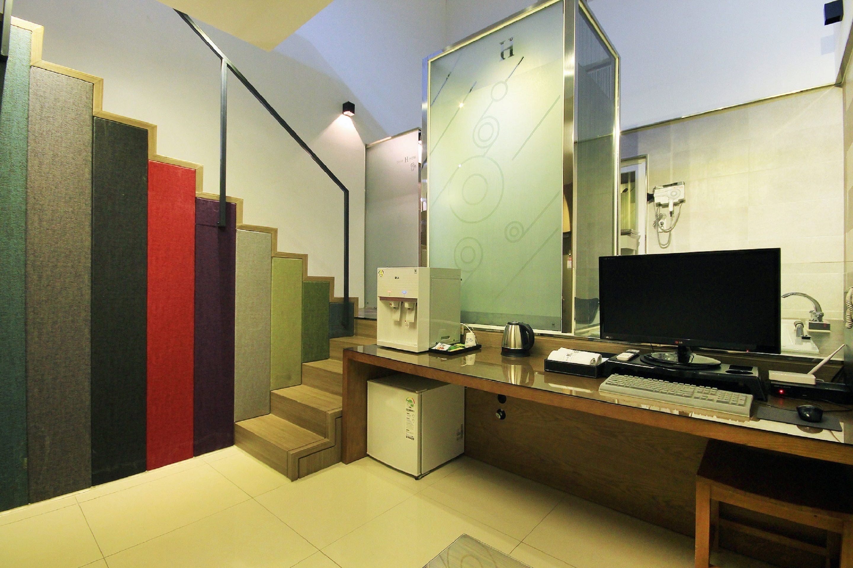 A modern hotel room with a wooden desk, a computer, and a coffee machine.