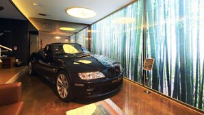Un coche descapotable negro estacionado dentro de un edificio con un amplio ventanal que muestra bambú.