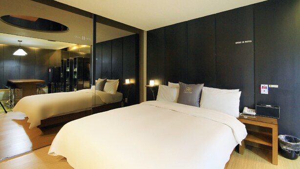Habitación de hotel con dos camas, un espejo, una mesita y un cesto de basura.