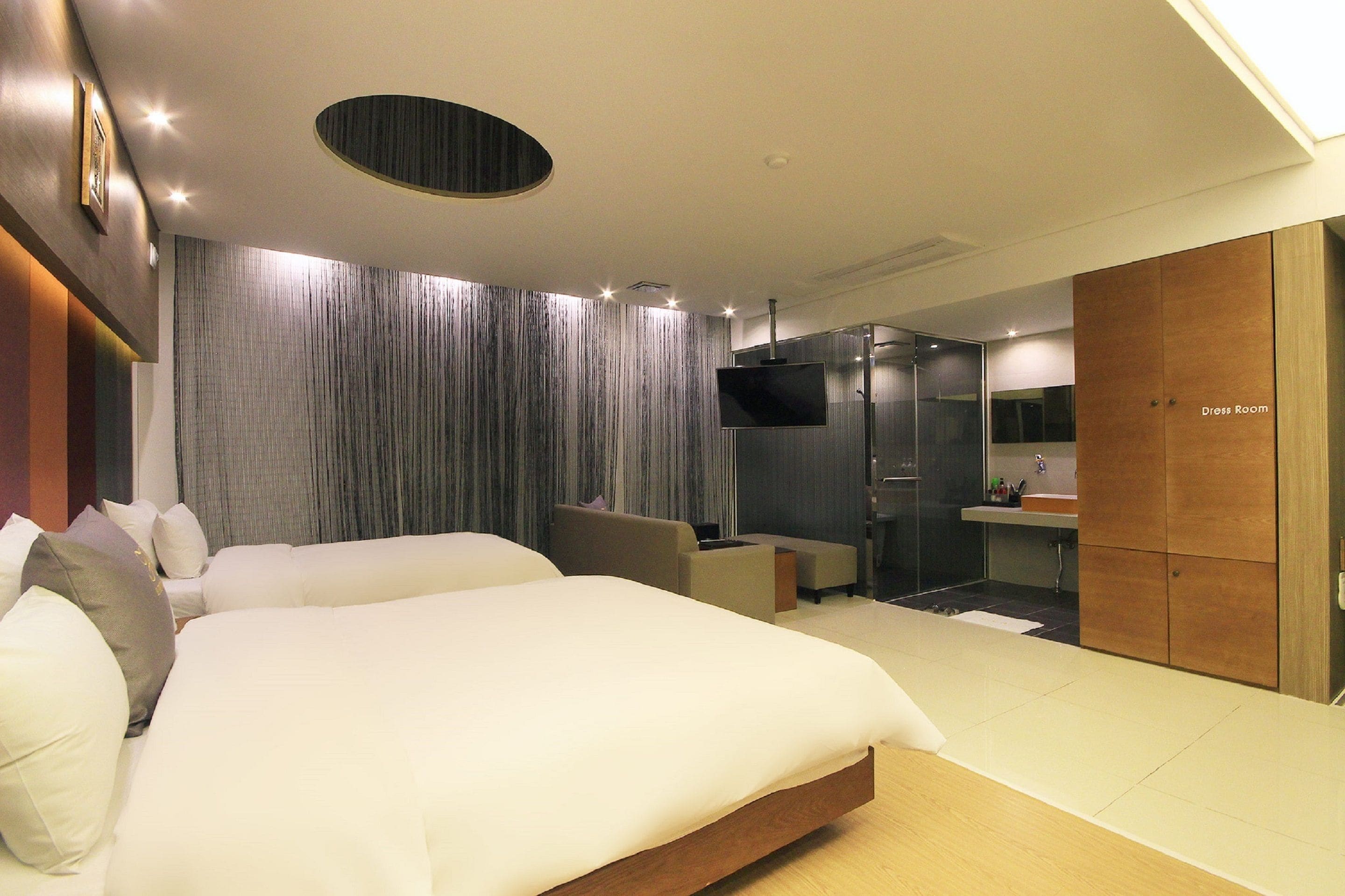 A modern hotel room with a large bed, a seating area, a TV, and a shower.