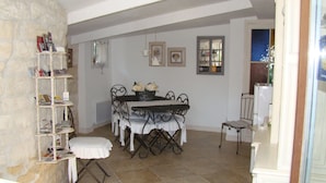 A dining area with a table set for four, surrounded by chairs, a white bench, and a bookshelf with books and magazines. - Lou Ventoulet (Mouries)