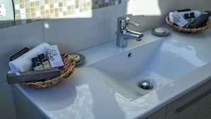 A bathroom with a white sink, a mirror, and a tiled backsplash. There are two baskets on the sink, one containing toiletries and the other a towel.