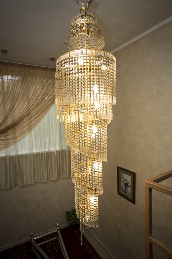 A chandelier with multiple tiers of crystals hanging from the ceiling. - Hotel Ajour (Almaty)
