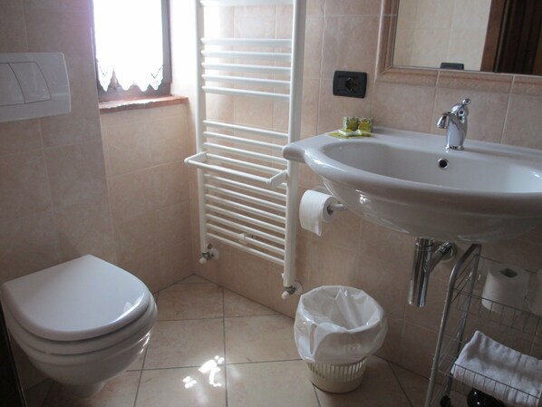 Un baño con inodoro, lavabo y un perchero para toallas.
