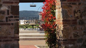 Une entrée en arc donnant sur un patio, avec une table et des chaises, et un paysage montagneux en arrière-plan.