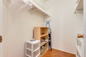 Ein schmaler Flur mit einem Holzregal, einer weißen Kunststoffablage und einer an der Wand stehenden Leiter.