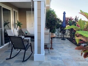 A patio area with a seating arrangement, including a rocking chair and a table with chairs. - Oceanview Townhome w/ Pool Near Beaches & Shops (Kailua-Kona)