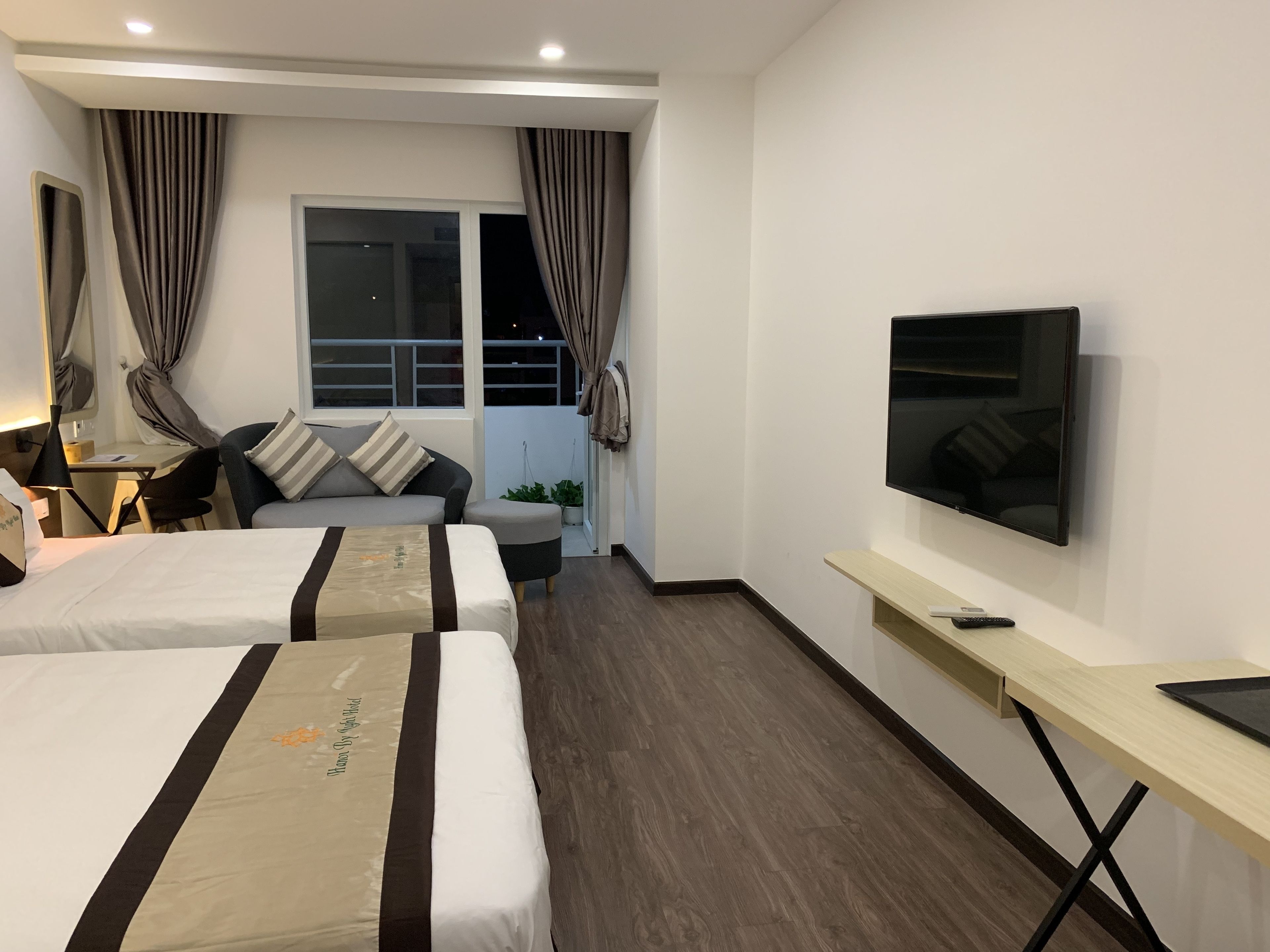 Habitación de hotel con dos camas, un escritorio, un televisor y una ventana con cortinas.