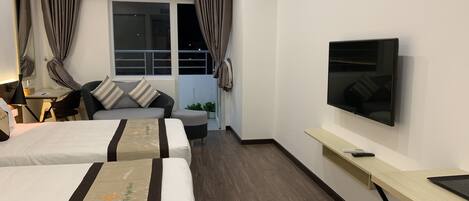 A hotel room with two beds, a desk, a TV, and a window with curtains.