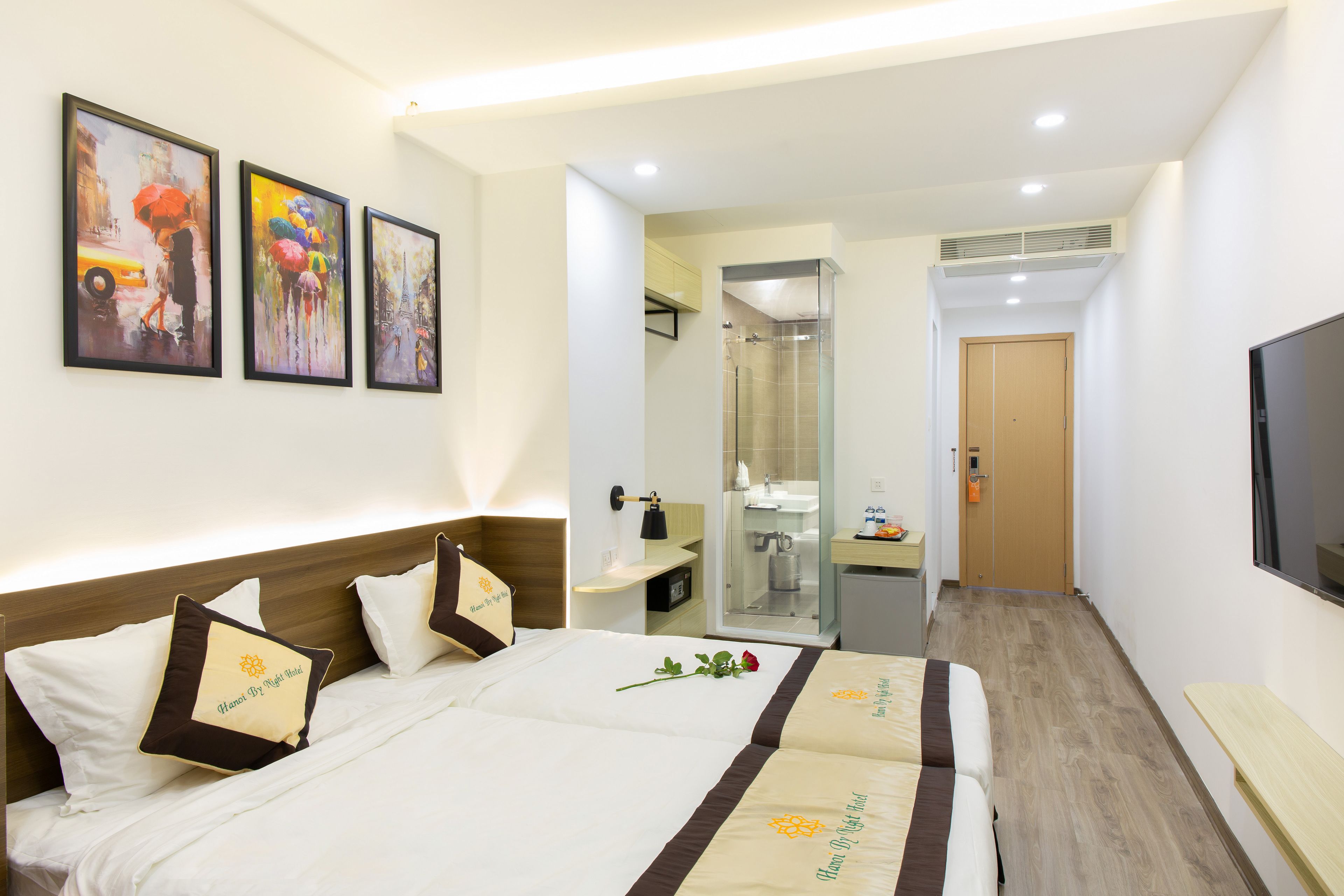 A hotel room with a bed, a desk, a TV, and a bathroom visible through an open door.