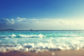 Ein Strand mit Wellen und einer entfernten Insel.