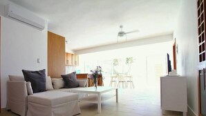 Una sala moderna con sofá, mesa de centro y un comedor al fondo.