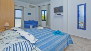 Una habitación de hotel con cama, televisión, sofá y ventana.