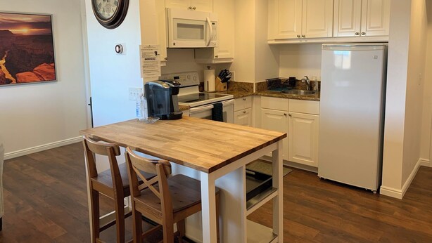 Una cocina con armarios blancos, una mesa de madera y un reloj en la pared.