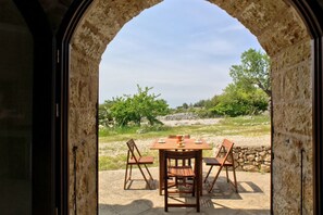 An outdoor dining area with a stone archway, a wooden table, and four chairs.