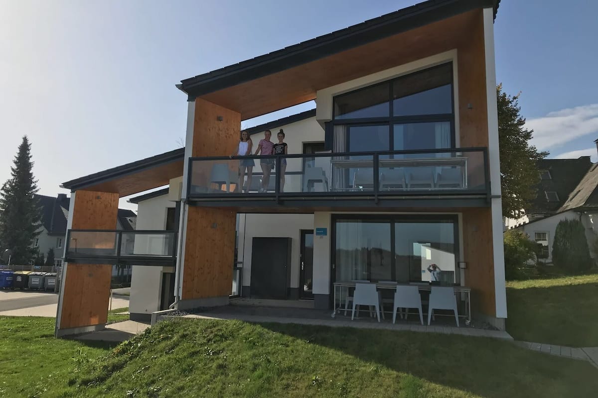 A modern two-story building with a balcony, large windows, and a flat roof.