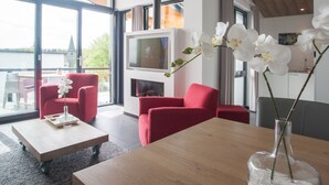 A modern living room with red sofas, a wooden coffee table, and white orchids in a vase. - Villas Winterberg (Winterberg)