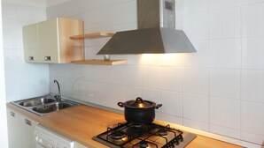 Een keuken met een fornuis, spoelbak en kasten.