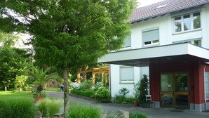 Ein modernes Gebäude mit überdachter Eingangspartie, umgeben von gepflegten Gärten und großen Felsen.