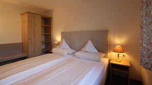 Ein Hotelzimmer mit einem großen Bett, einem Holzschrank, einem Nachttisch mit Lampe und einem blumigen Vorhang.