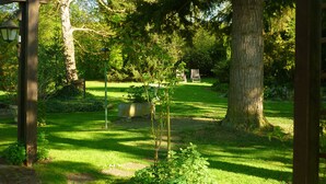 Ein Garten mit einer Holzpergola, einer Bank und einem großen Baum.