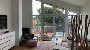Una sala de estar moderna con un amplio ventanal corredizo que da a un patio exterior.