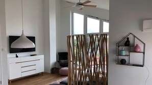 Un salón moderno con televisor blanco, muebles de madera y un comedor con mesa y sillas.