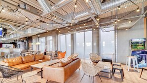 A spacious, modern lounge area with leather sofas, wicker chairs, and a bar area with a neon sign. - Ecla Paris Massy Palaiseau (Palaiseau)