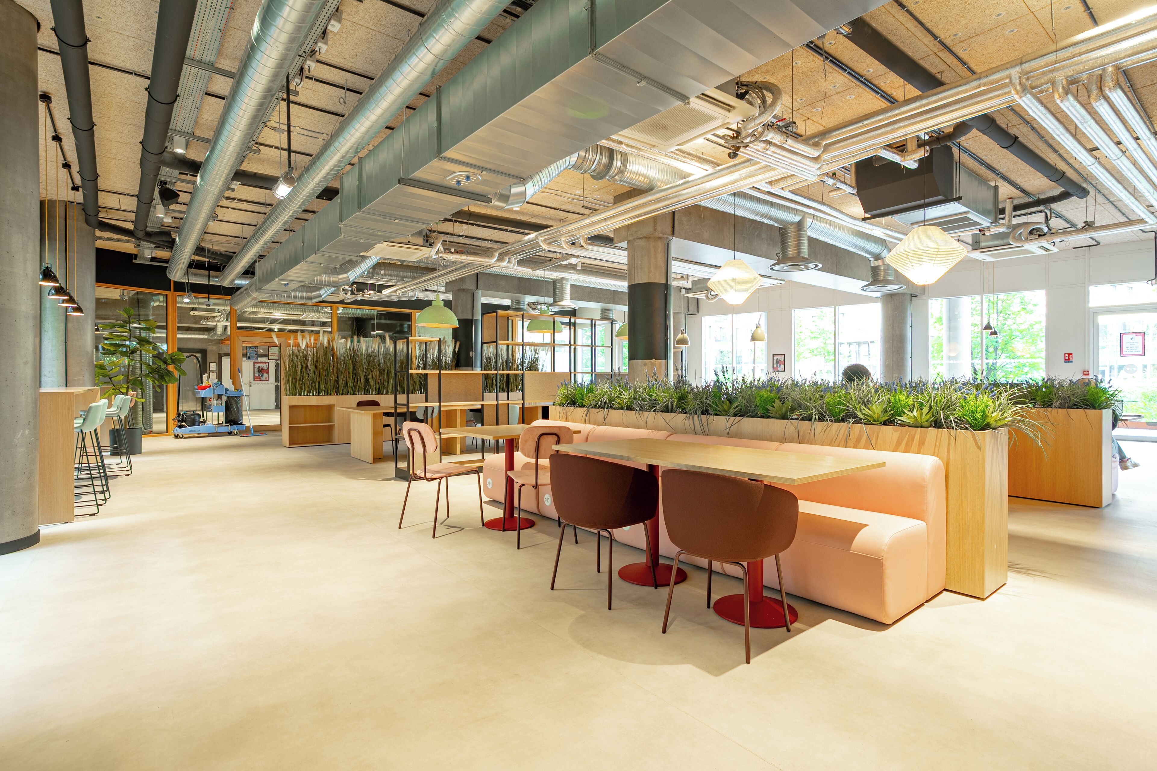 A modern office space with a long wooden table, multiple chairs, and a seating area with a sofa.
