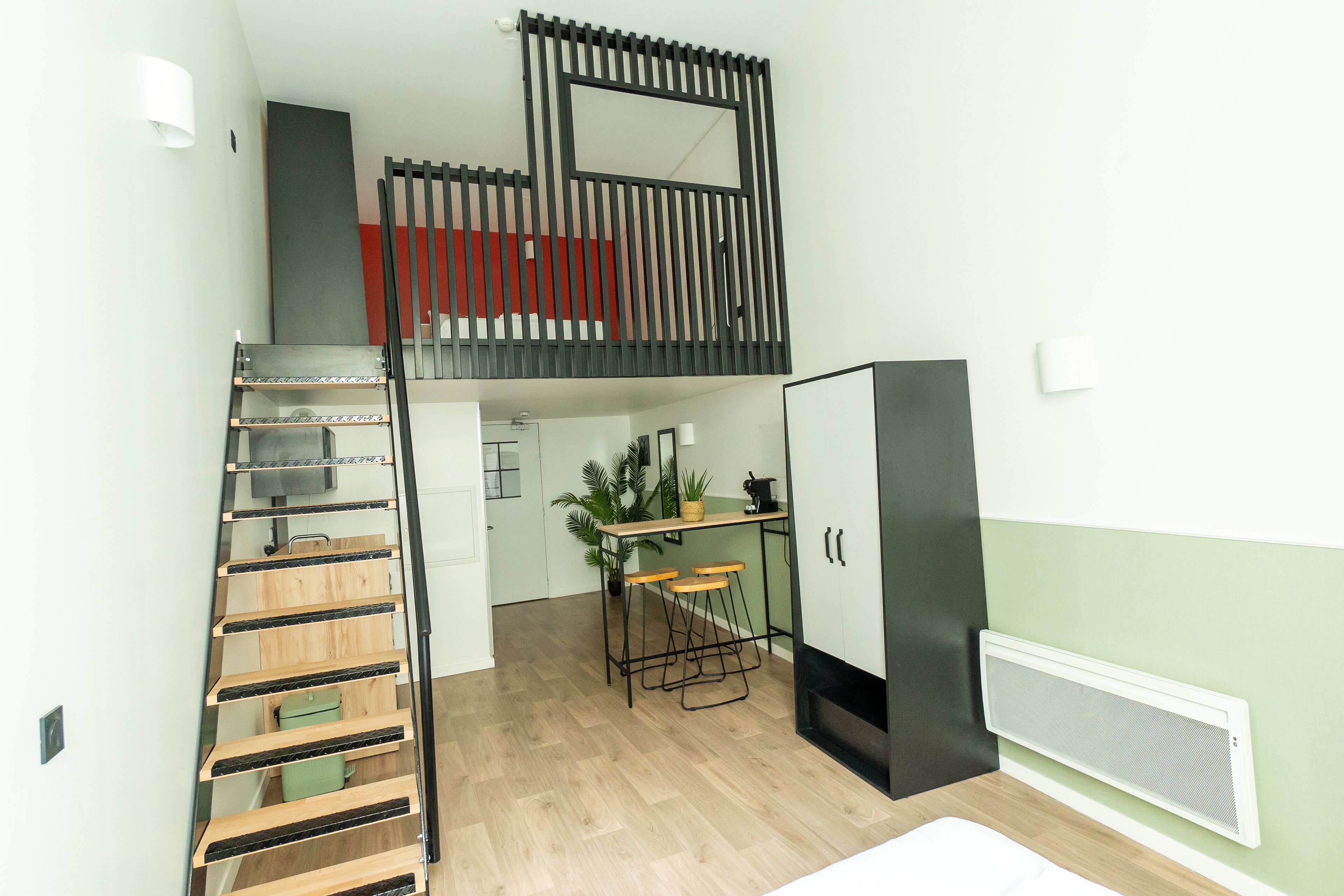 Una cocina compacta con una escalera de madera, un pequeño comedor y un refrigerador empotrado.