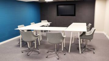 A conference room with a white table, grey chairs, and a blue accent wall.