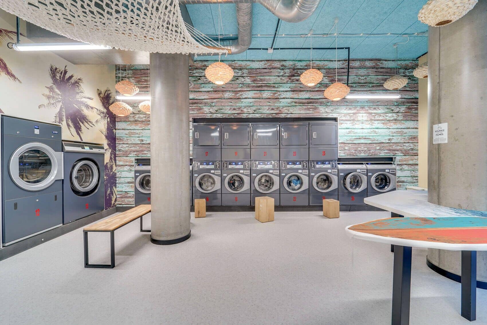 A modern laundromat with multiple washing machines, a bench, and a table with a map.