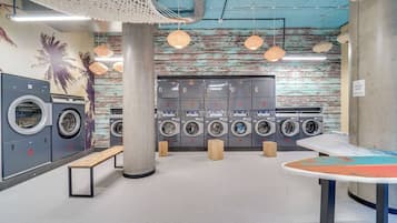 A modern laundromat with multiple washing machines, a bench, and a table with a map.