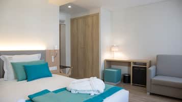 Habitación de hotel con cama, escritorio, silla, armario y cesto de basura.
