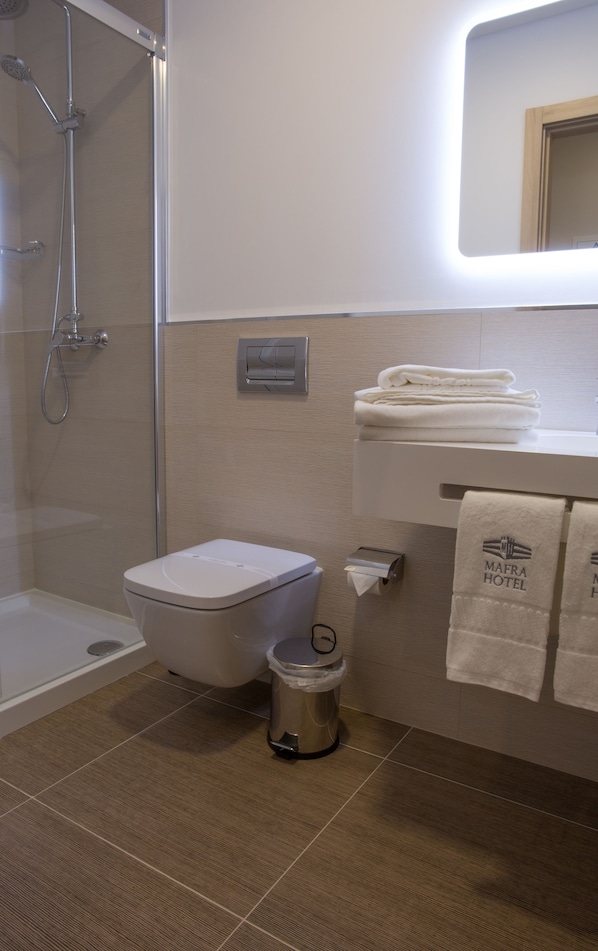 Un baño moderno con ducha, inodoro y un cubo de basura.