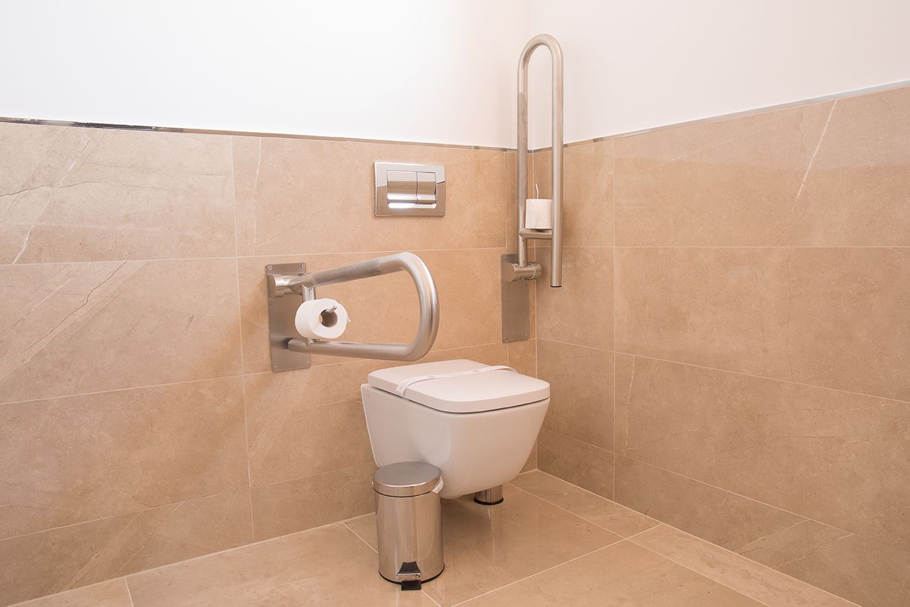 Ein modernes Badezimmer mit Toilette, Handtrockner und Mülleimer.